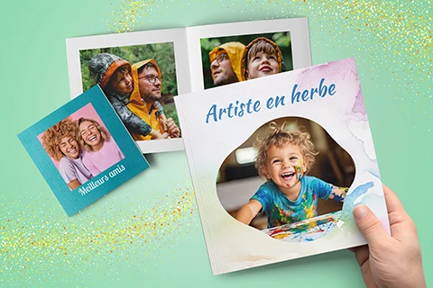 main tenant un livre photo Quickbook avec deux autres livres photo en arrière-plan